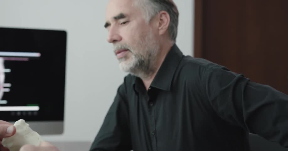 A man explains something to another man by putting pieces of a model together