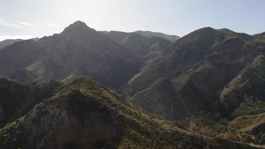 Forest covered mountain range and valleys under sunny sky