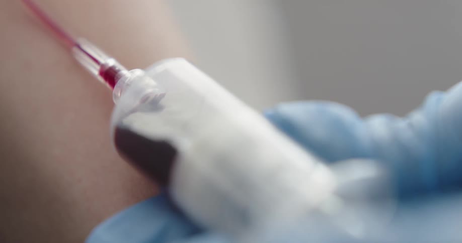 A person having their blood drawn by a person wearing blue latex gloves