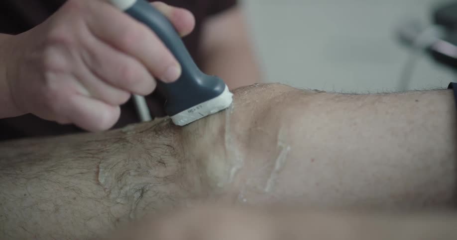 A medical professional does an ultrasound on a mans knee