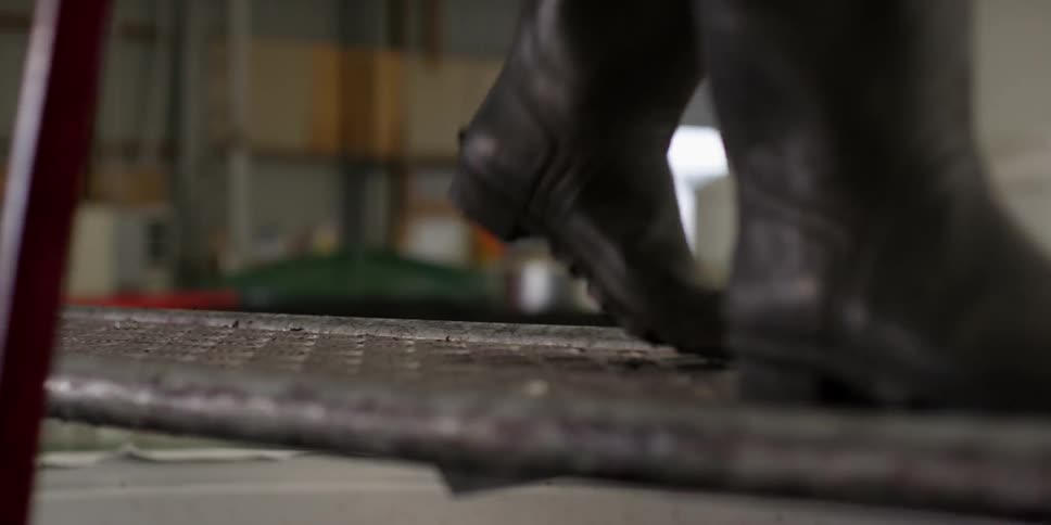 Boots walking on a grate in a large garage