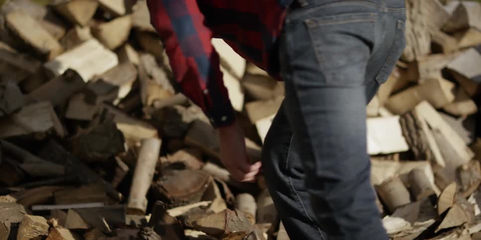 A man sorts chopped logs outside