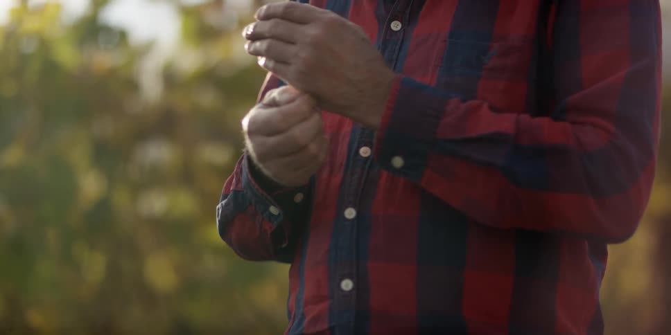 A man in a plaid shirt stands outside