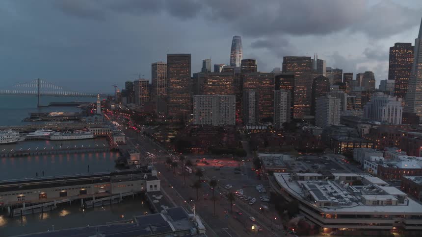 The cars drive past the city at sunset
