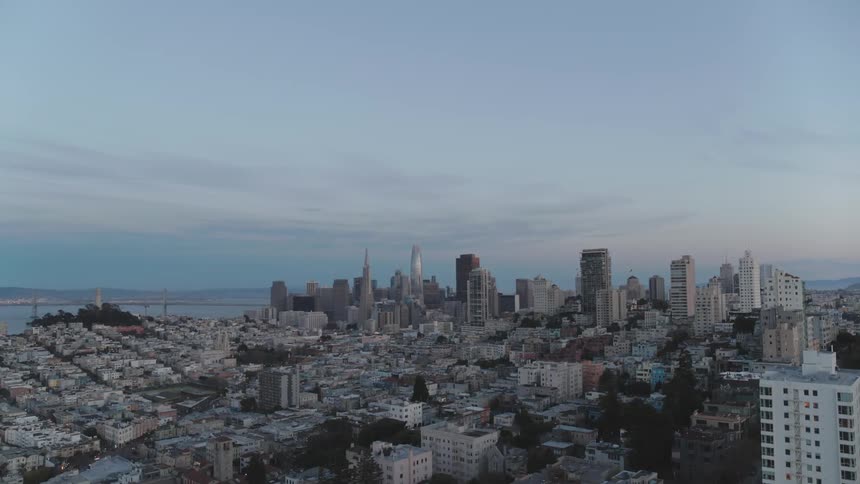Skyline of the city with tall buildings and skyscrapers next to the sea at dusk