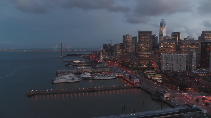 Boats sit beside tall sky scrapers in the harbor of a large city