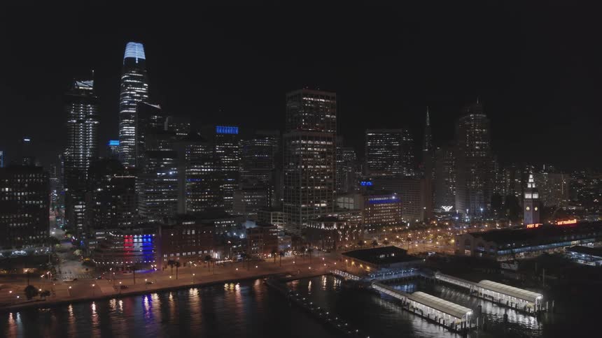 Downtown skyscrapers lights reflect off water near docks