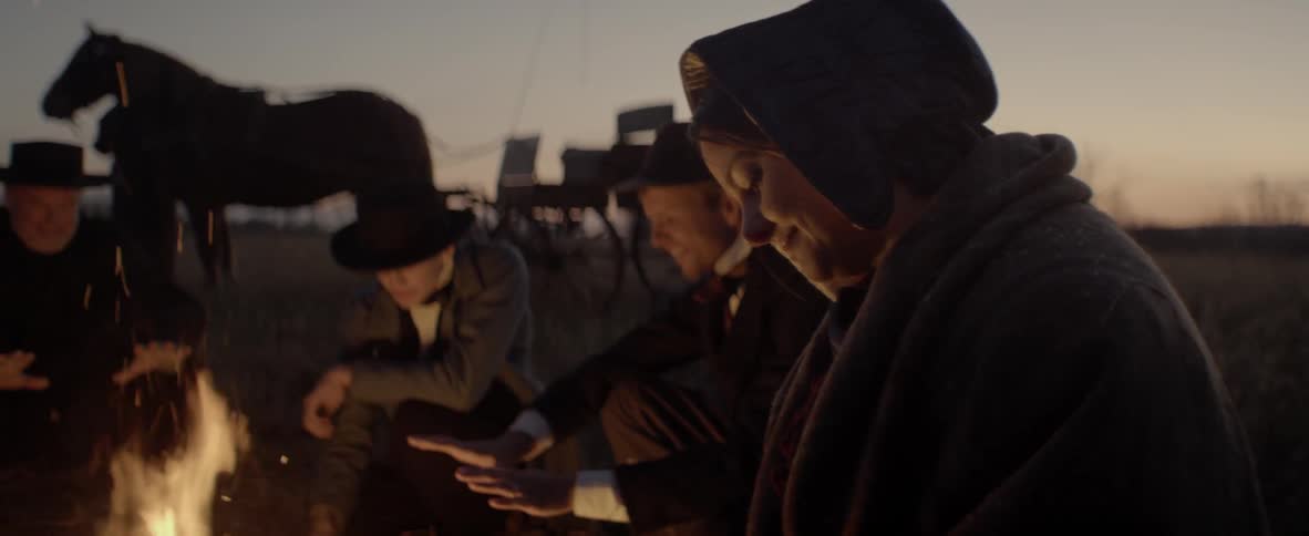 A group of people sit in front of the camp fire