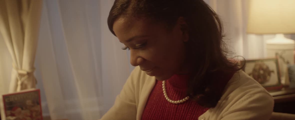 A girl wearing a pearl necklace smiles at something off screen