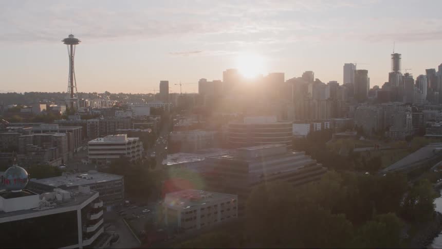 Sun peaks over skyscrapers downtown near water
