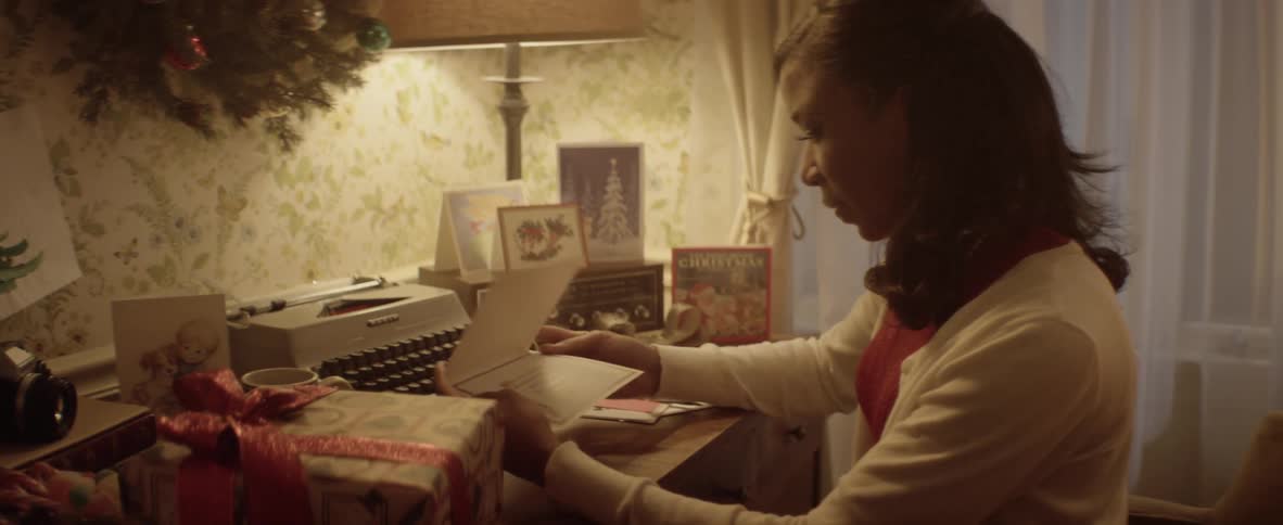 A woman sits and her desk and reads a christmas card