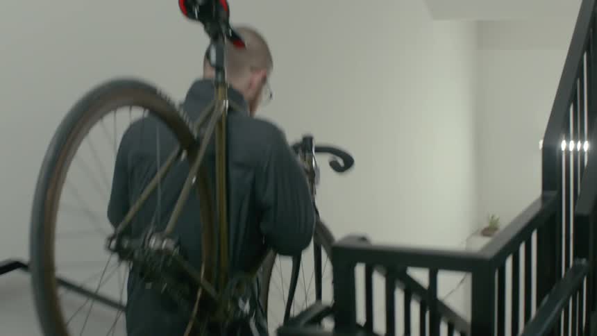 A man is carrying his bicycle down some stairs