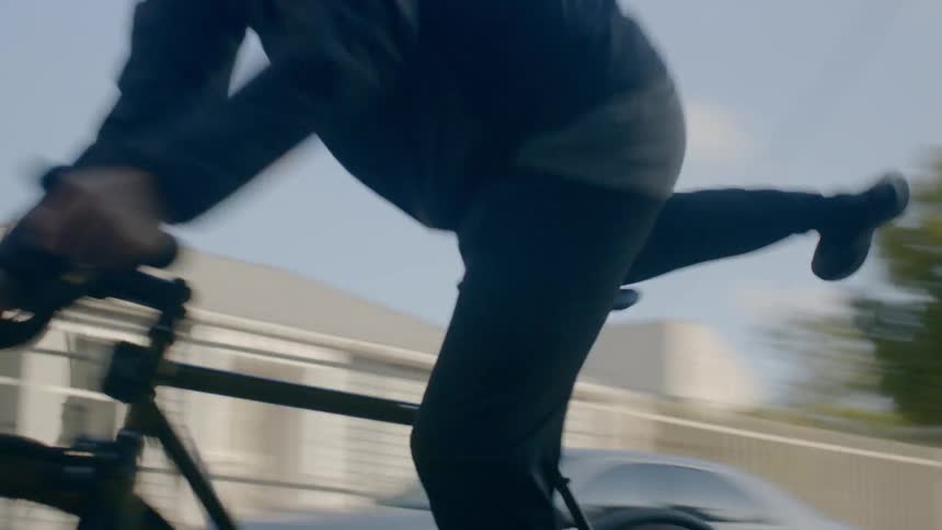 Man jumps on his bike and rides away in the city during daylight