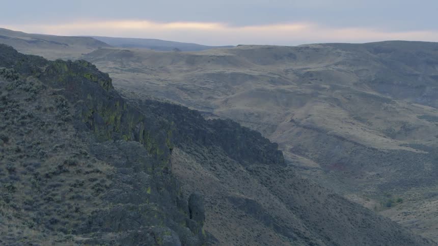 A mountainous landscape is dotted with scrub brush