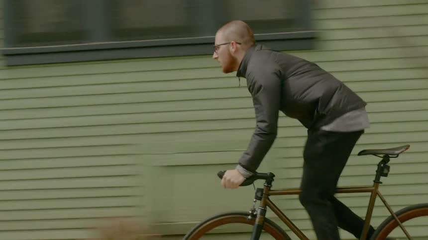 A man stands up while pedaling a bicycle on a city sidewalk
