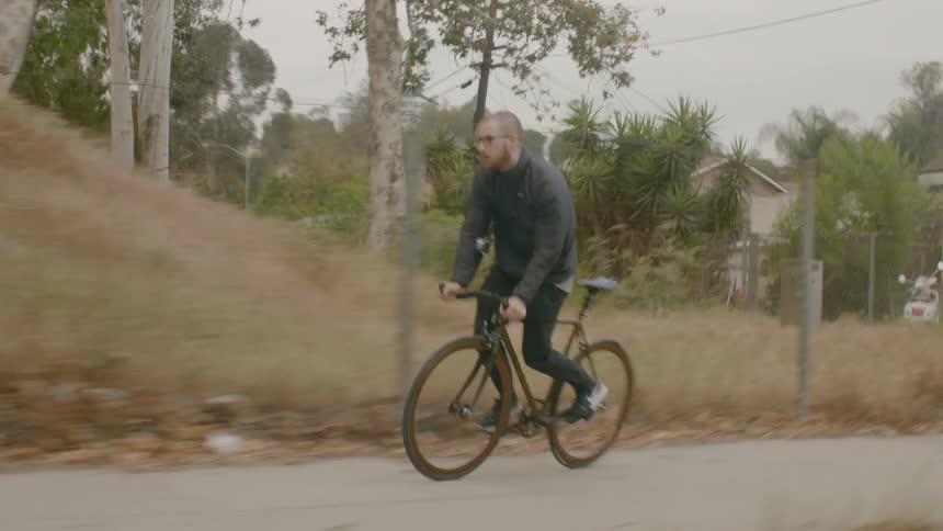 A man rides his bike down a sidewalk