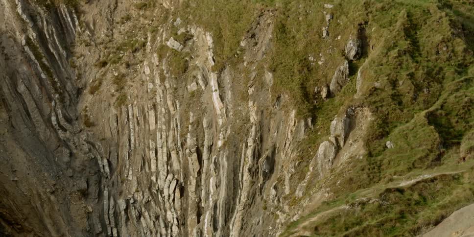 The mountains lead to a cliff covered in green
