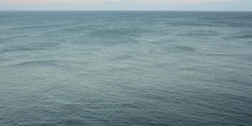 Countless calm waves roll across the surface of an expansive ocean as water is all that can be see with no land in sight