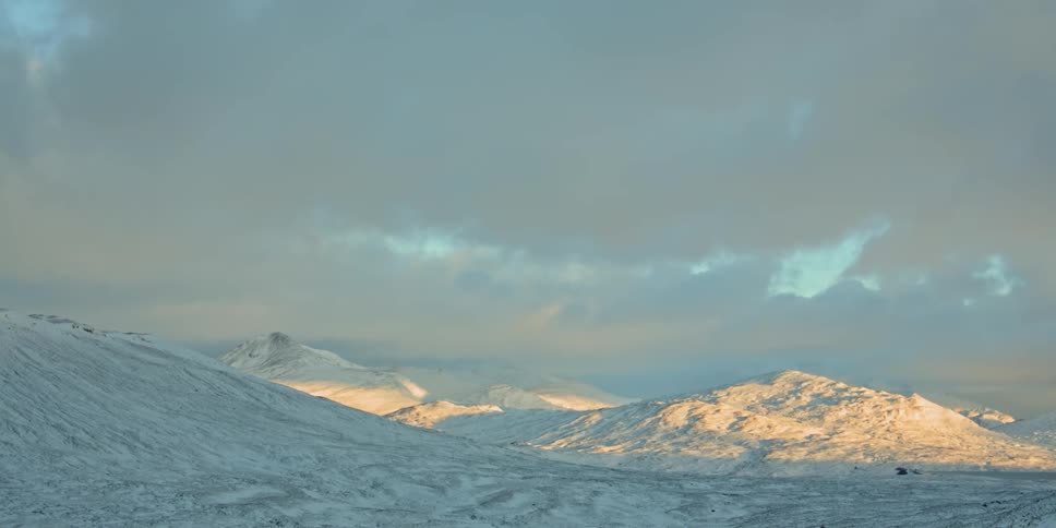 Mountains and hills sit under a cloudy sky