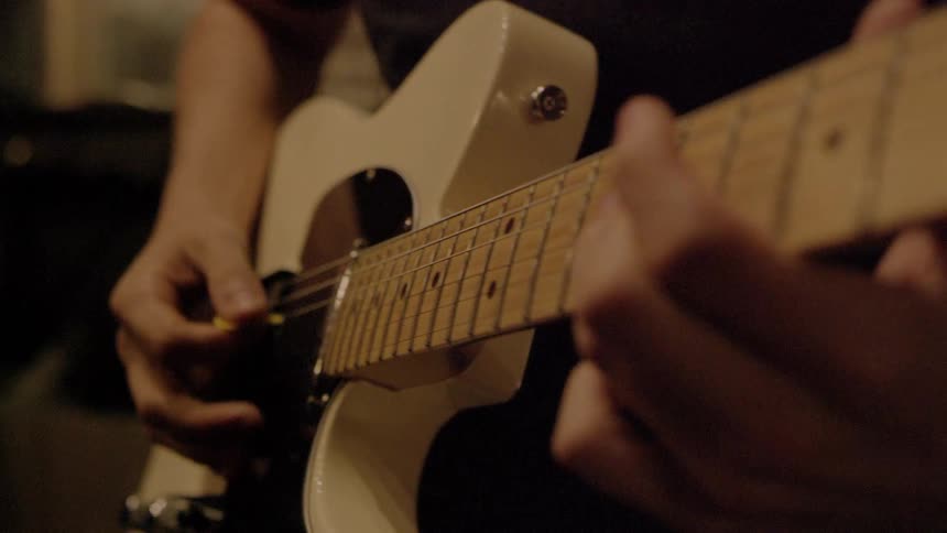 A person strums an electric guitar