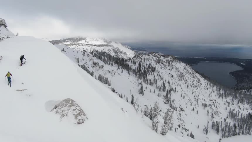 People in skis walk up a snow covered mountain