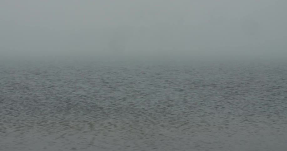 Mist floats above a rippling body of water