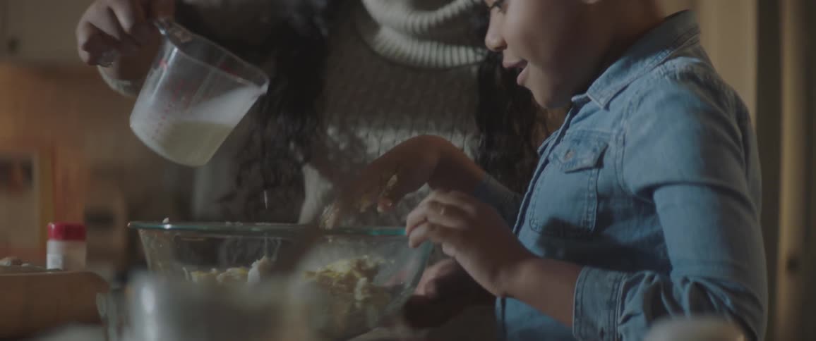 Mom and daughter mix dough in the kitchen