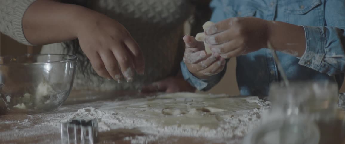 A girl pulls out a gingerbread man from dough