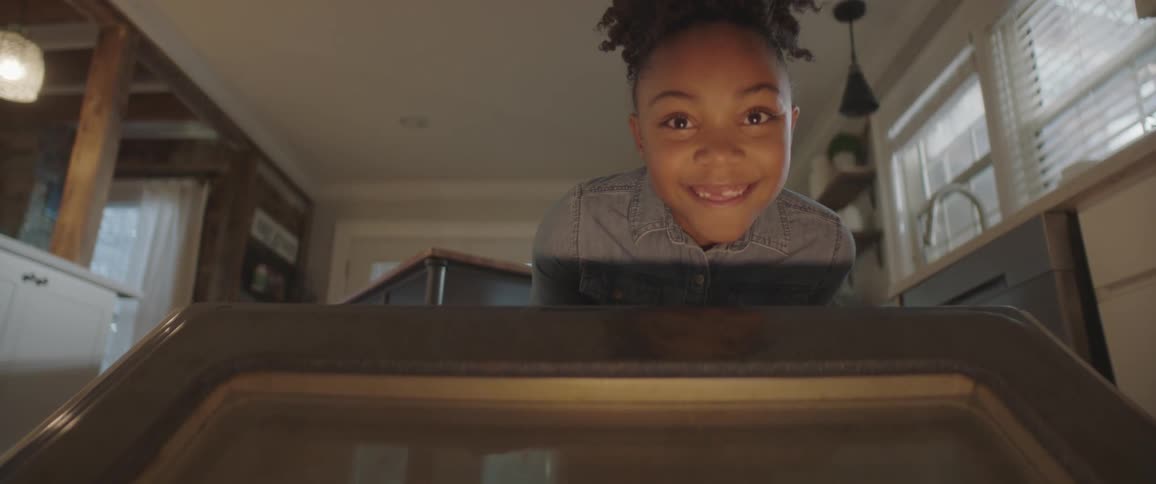 A girl looking inside an oven then closing it