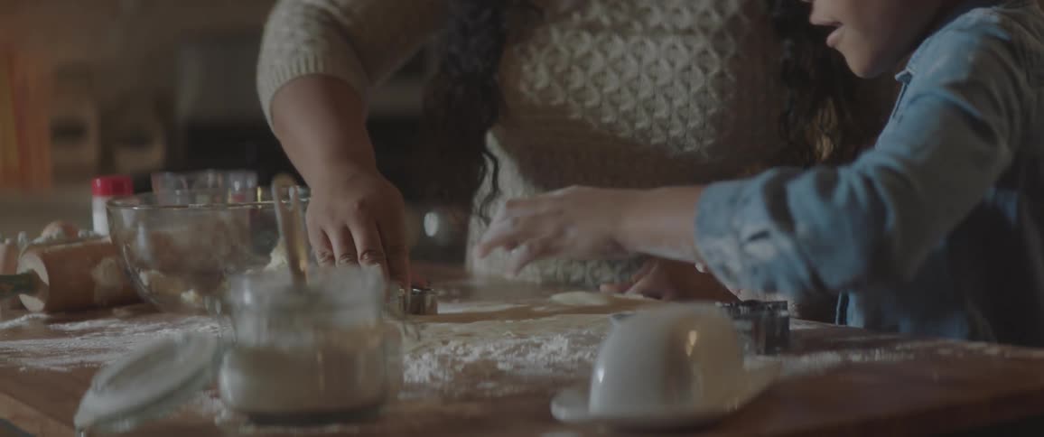 A girl and woman cut cookies out of dough