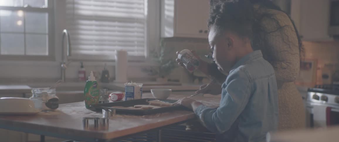A mother and child work on baking in a kitchen