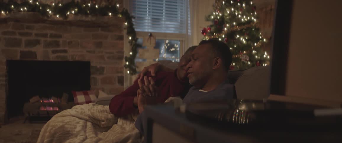 Father and mother cuddling in front of the fireplace at christmas night