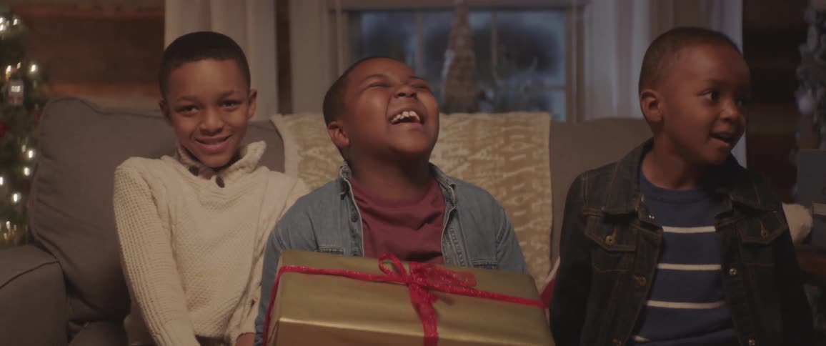 Kids are sitting on a couch with presents