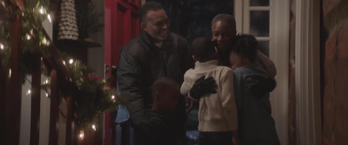 Parents hug each of their children in front of the house