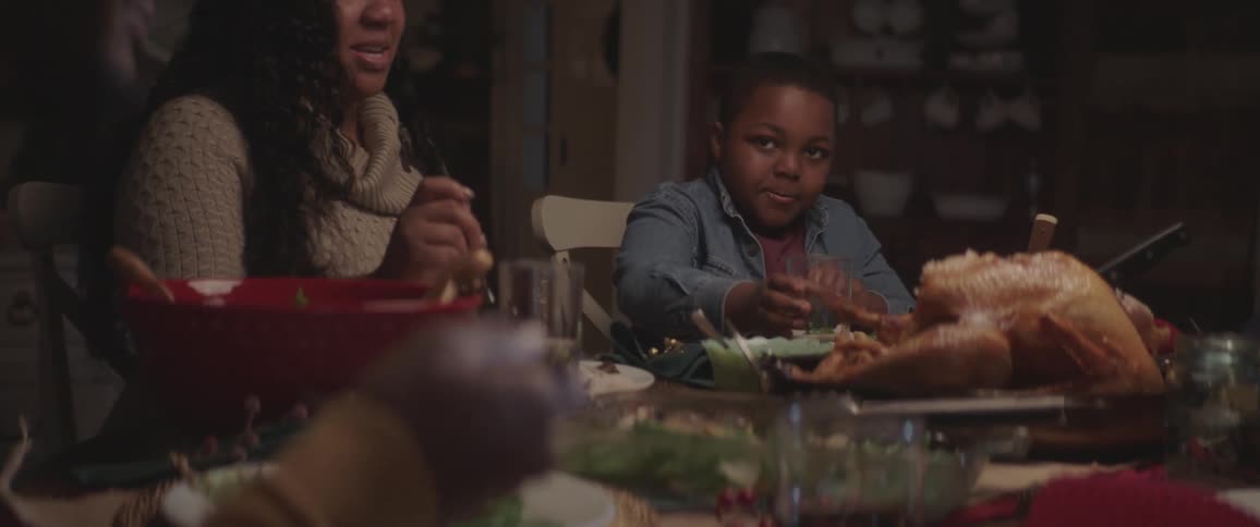 A family sits at a table and has thanksgiving dinner