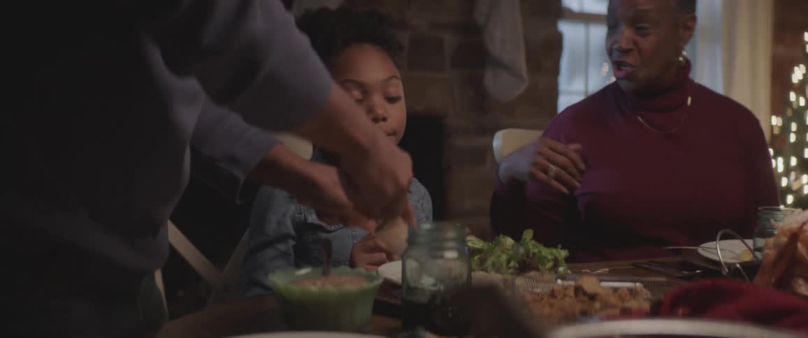 A family sitting around a dining table watching as the turkey is cut