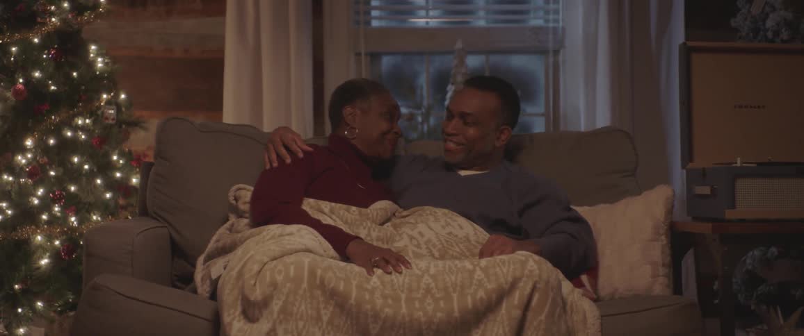 A man and woman sit on the couch and talk and cuddle
