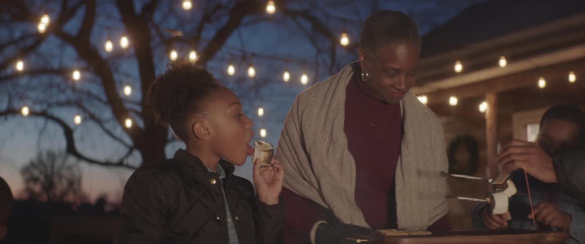 A family eats smores outside in their backyard at night