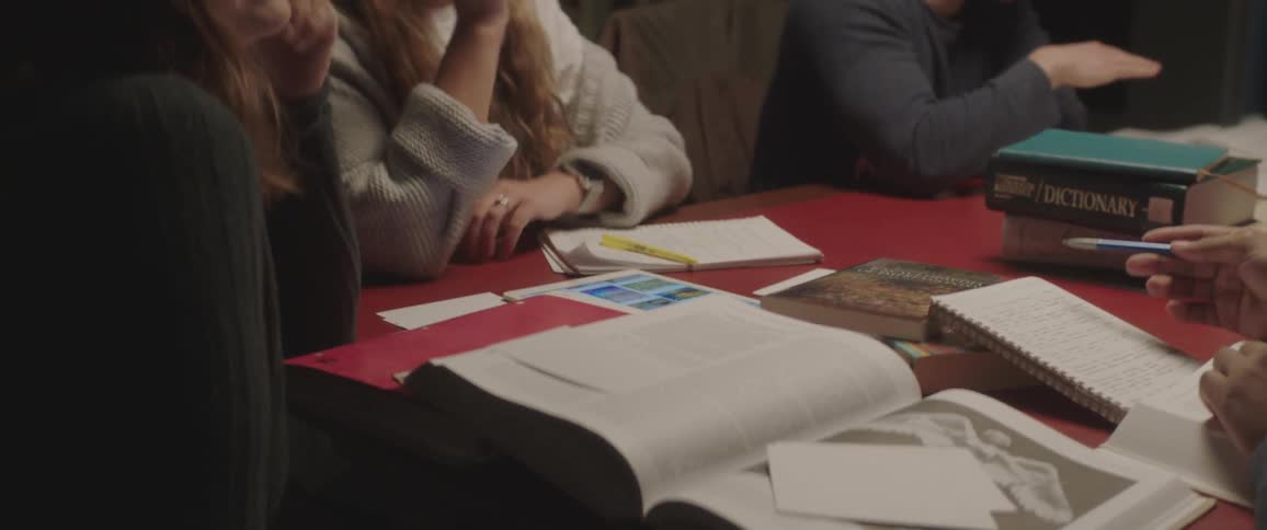 Several people are sitting around a table with books on it