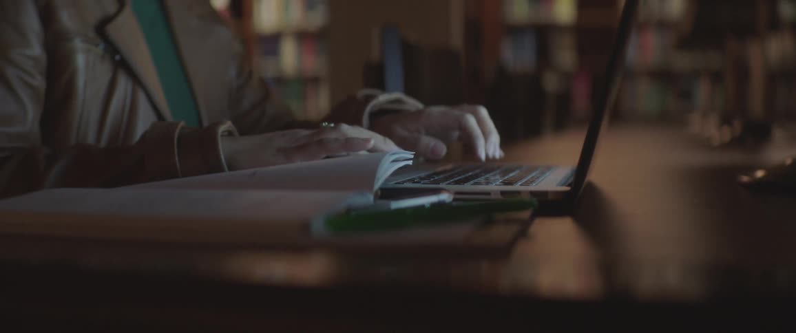 A woman is typing on her laptop while sitting at a desk