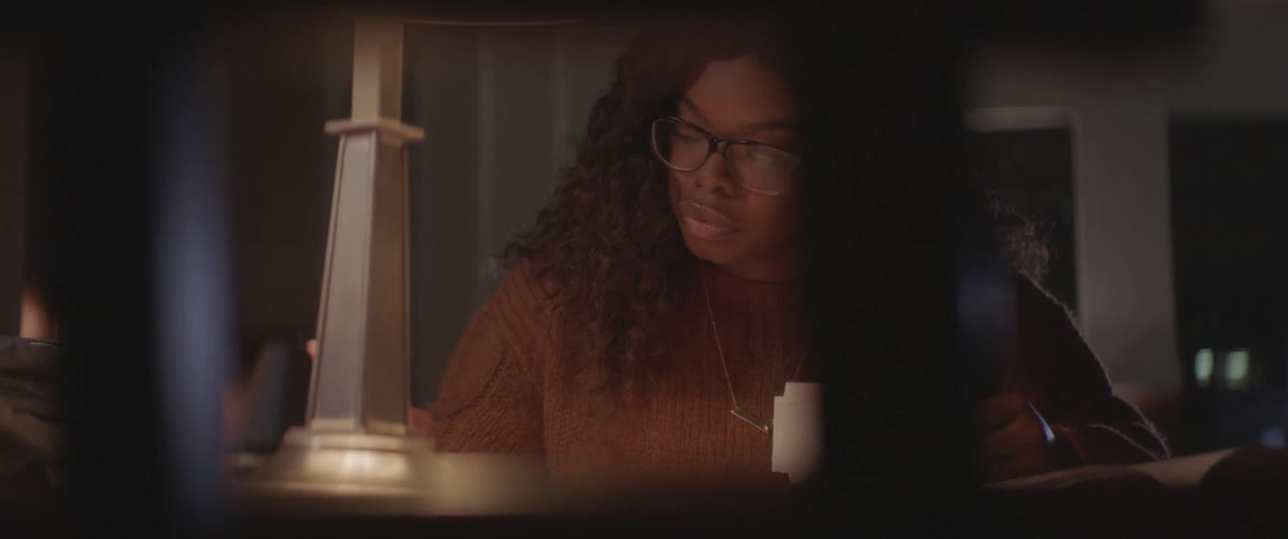 Black woman sitting at the table writes down in the library at night