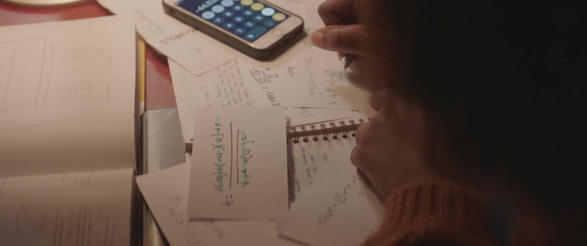 A person is writing on paper at a desk