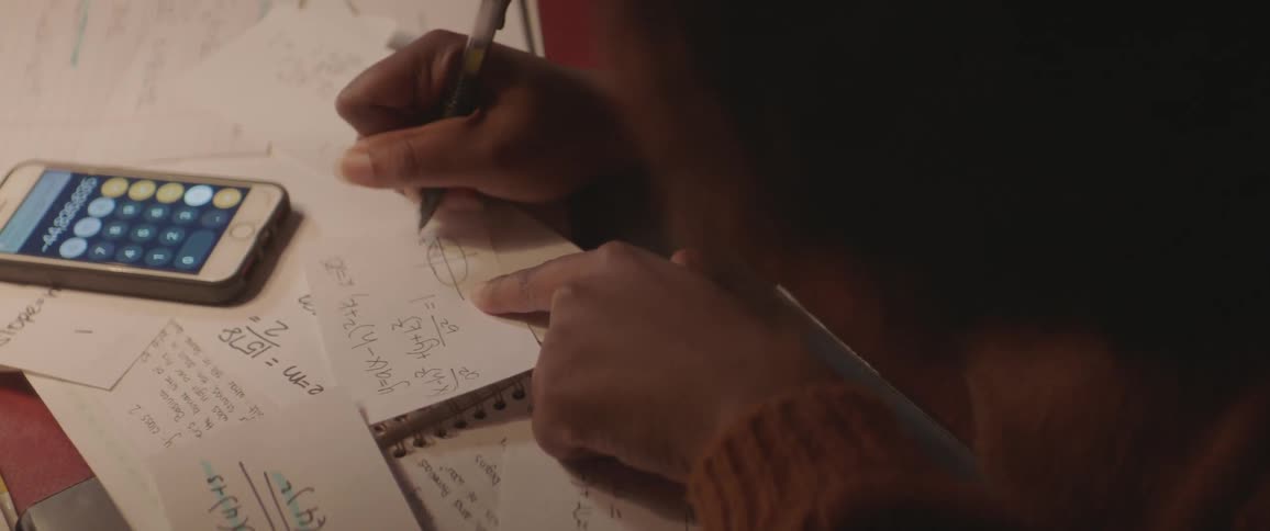 A woman is writing some calculations on a piece of paper