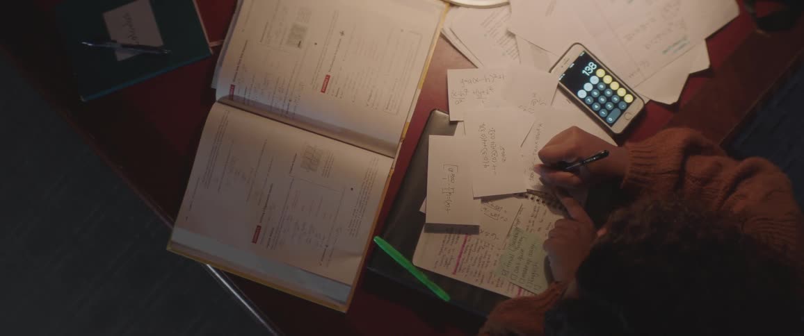 A person is doing homework while looking at a book