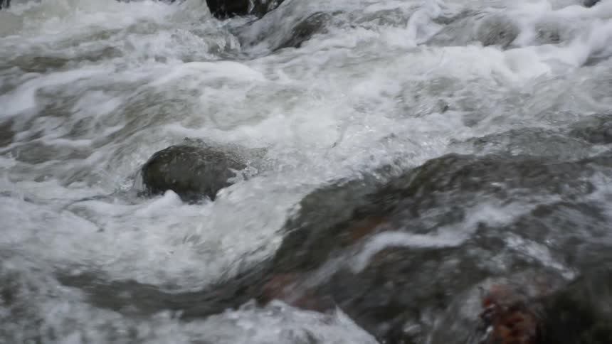 Waves rush over boulders in a river