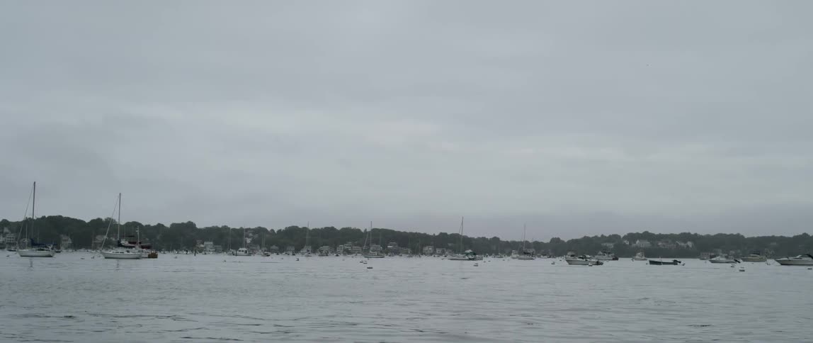 Several sail boats are anchored in a harbor with calm water