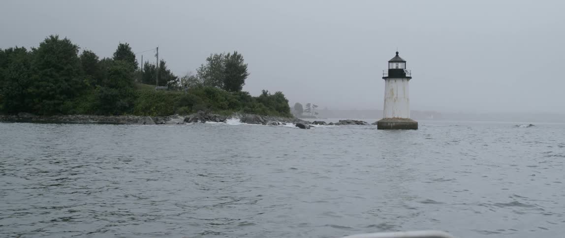 A light house in the water with trees on the shore