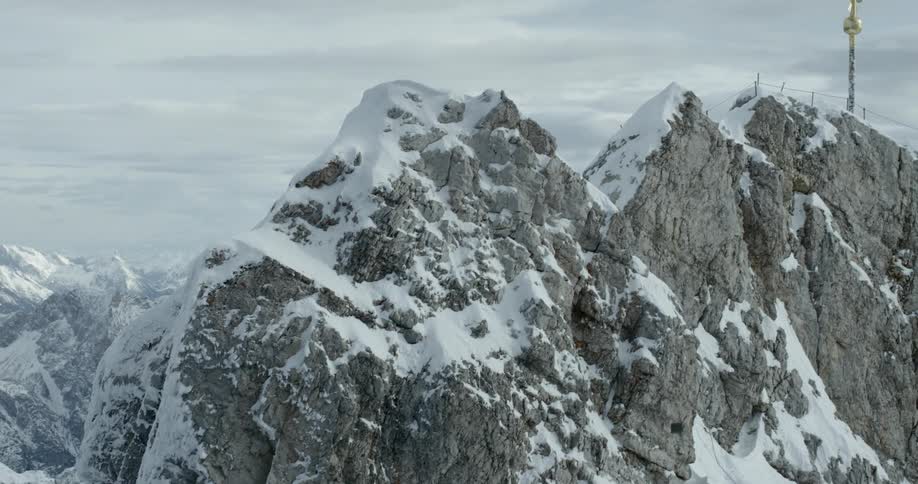 A large gold cross at the top of a snow covered mountain peak
