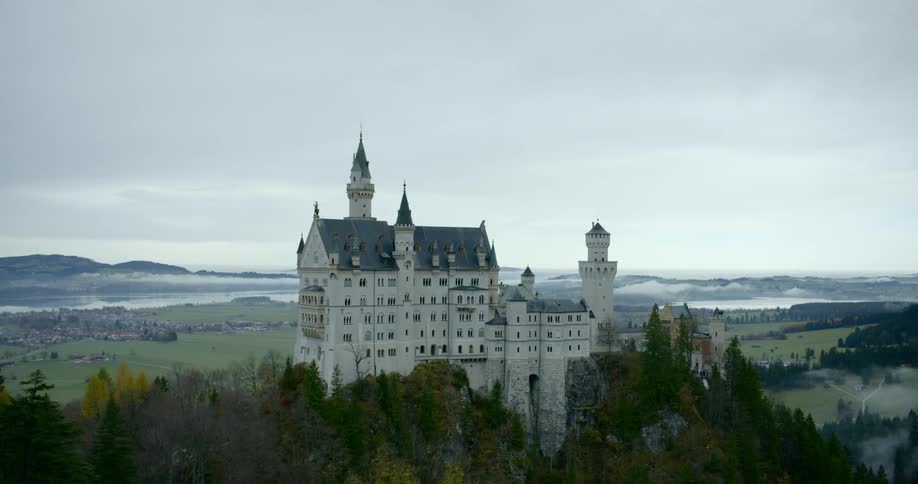 Chateau on forest covered mountain peak overlooking fog cover valleys