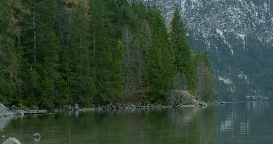 Water reflects forests and mountains at shoreline